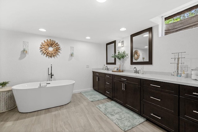 120 25th St, Minot, ND 58701 - full bathroom with double vanity, a freestanding tub, wood finished floors, and recessed lighting