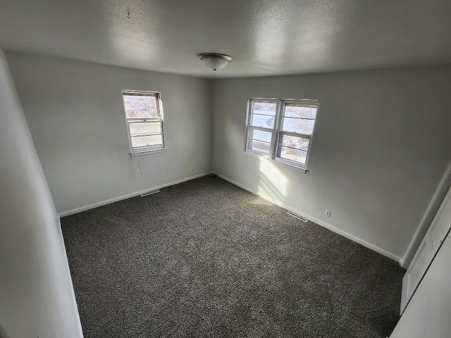 607 Main St, Minot, ND 58701 - empty room featuring dark colored carpet and a textured ceiling