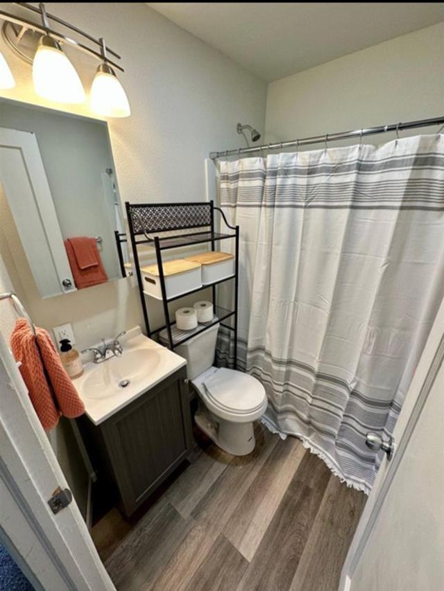 607 Main St, Minot, ND 58701 - full bath with wood finished floors, vanity, and a shower with curtain