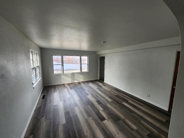 607 Main St, Minot, ND 58701 - spare room with dark wood-style flooring, a textured ceiling, and arched walkways