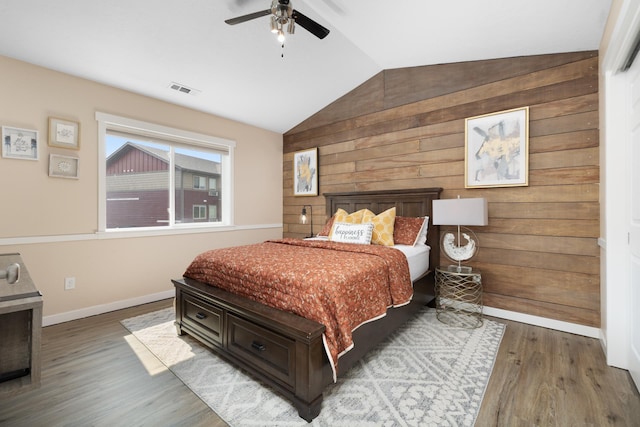 4007 Crossing St, Minot, ND 58701 - bedroom featuring vaulted ceiling, wood finished floors, wooden walls, and ceiling fan