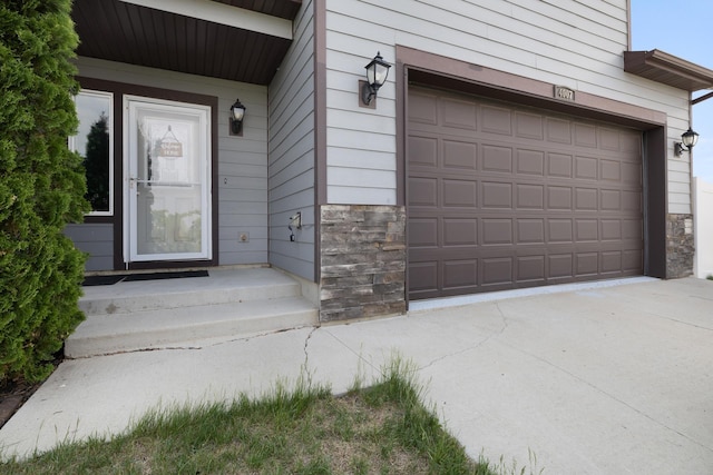 4007 Crossing St, Minot, ND 58701 - property entrance featuring stone siding, a garage, and driveway