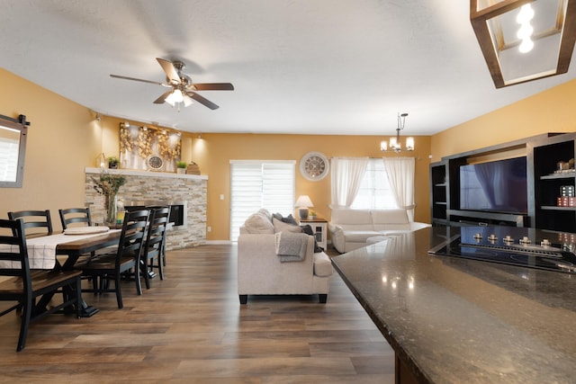 4007 Crossing St, Minot, ND 58701 - living room with a chandelier, a ceiling fan, dark wood-style flooring, and a stone fireplace