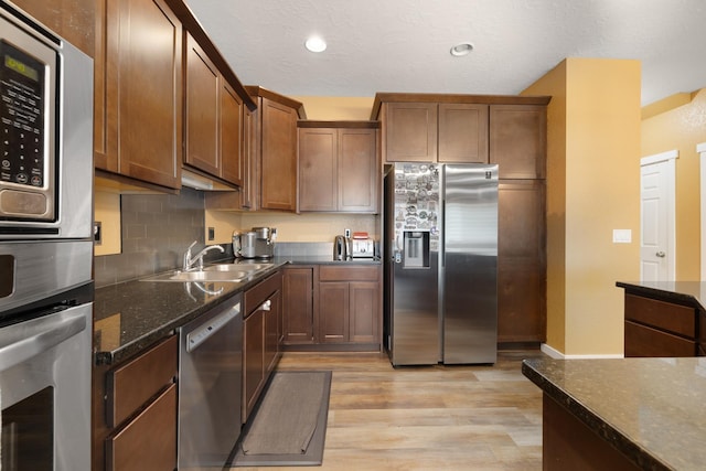 4007 Crossing St, Minot, ND 58701 - kitchen with appliances with stainless steel finishes, light wood finished floors, tasteful backsplash, dark stone counters, and recessed lighting