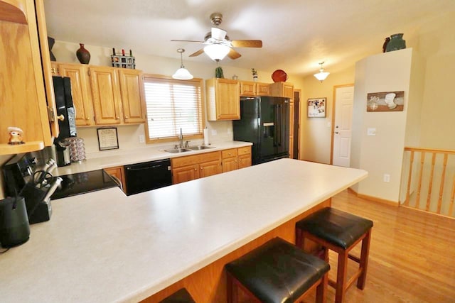 2033 14th St, Minot, ND 58703 - kitchen with black appliances, a peninsula, ceiling fan, light wood-type flooring, and a kitchen breakfast bar