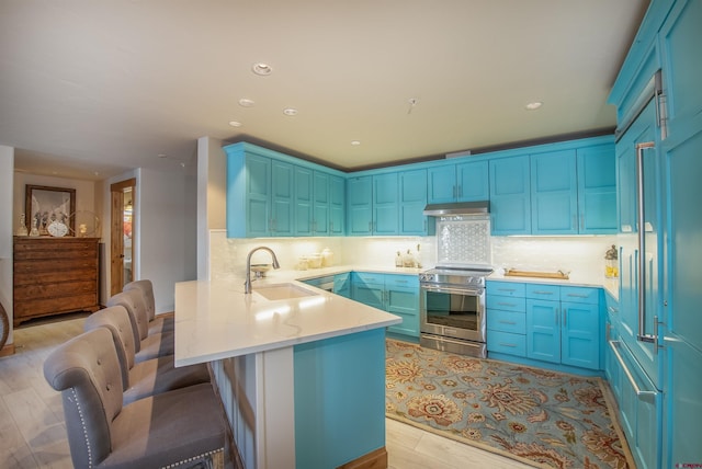 kitchen with a breakfast bar area, stainless steel electric range oven, sink, and light hardwood / wood-style flooring