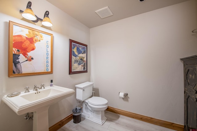 bathroom with hardwood / wood-style floors, toilet, and sink