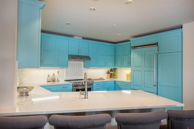 kitchen featuring a kitchen breakfast bar, blue cabinets, high end range, and kitchen peninsula