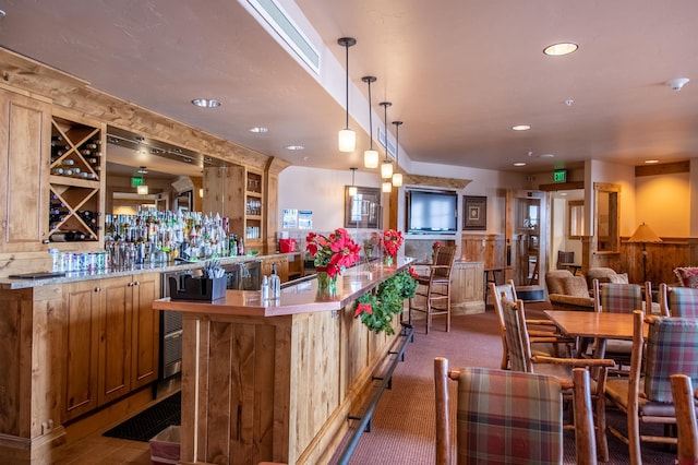 bar with hanging light fixtures and dark carpet