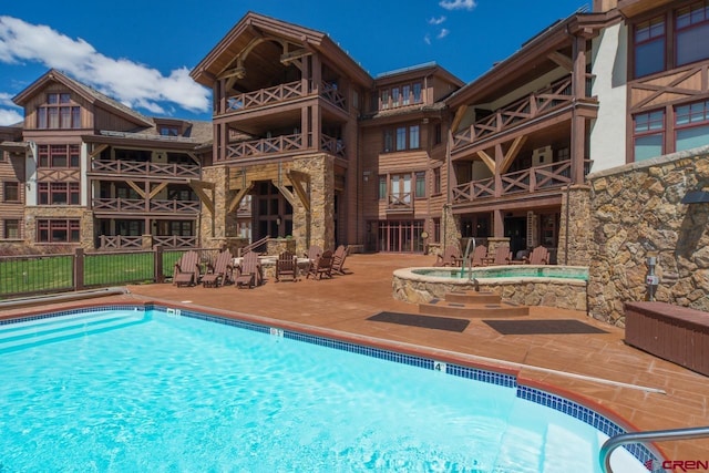 view of swimming pool featuring a community hot tub and a patio area