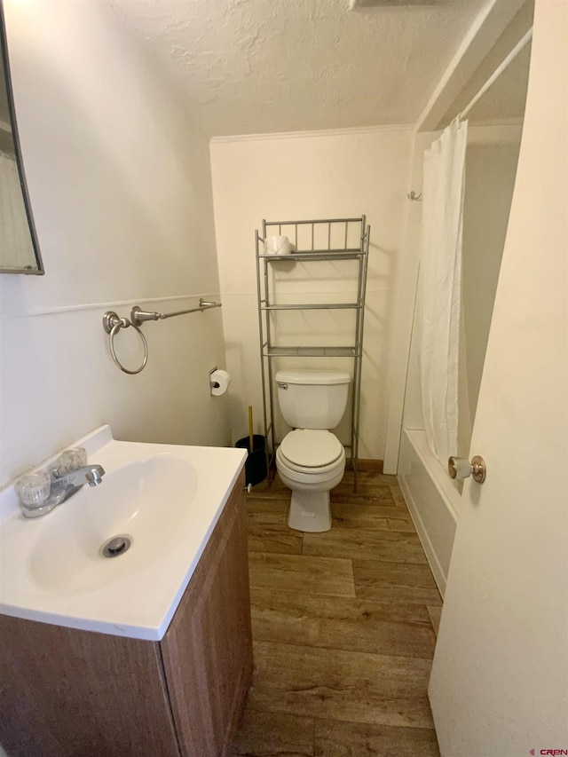 full bathroom featuring toilet, large vanity, hardwood / wood-style flooring, a textured ceiling, and shower / bath combination with curtain