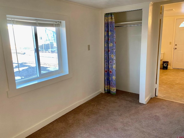 unfurnished bedroom with dark colored carpet and a closet