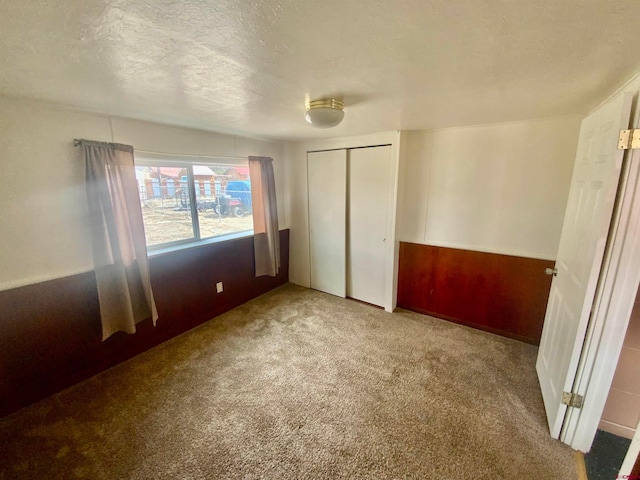 unfurnished bedroom featuring light carpet, a closet, and a textured ceiling