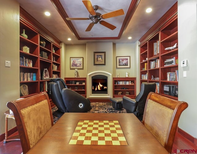 interior space with a raised ceiling, crown molding, ceiling fan, and built in shelves