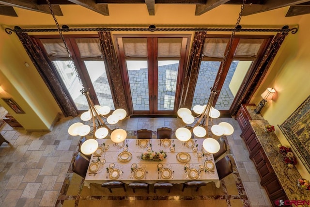 tiled entrance foyer with a chandelier, a high ceiling, french doors, and beam ceiling