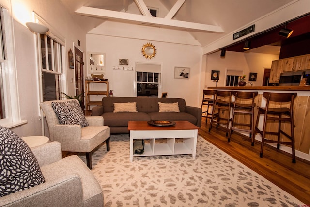 living room with a towering ceiling, beam ceiling, and light hardwood / wood-style flooring