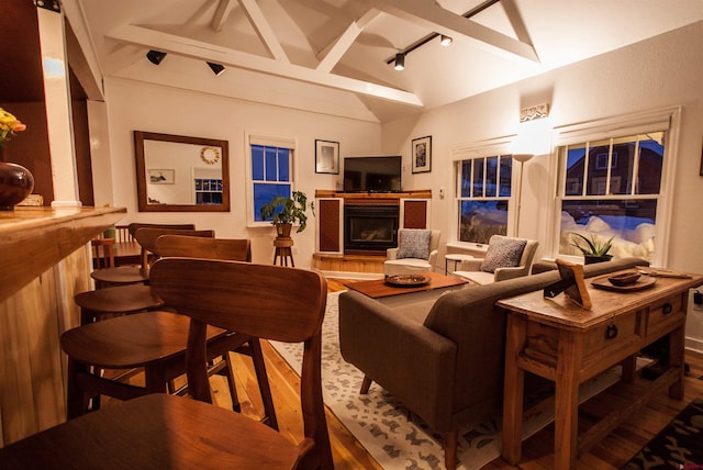 living room featuring track lighting, vaulted ceiling with beams, and dark wood-type flooring