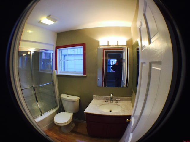 full bathroom with hardwood / wood-style flooring, toilet, combined bath / shower with glass door, and oversized vanity