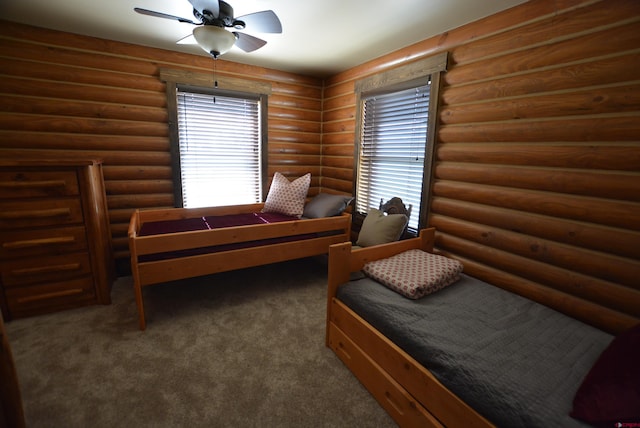 bedroom with log walls, ceiling fan, and dark colored carpet