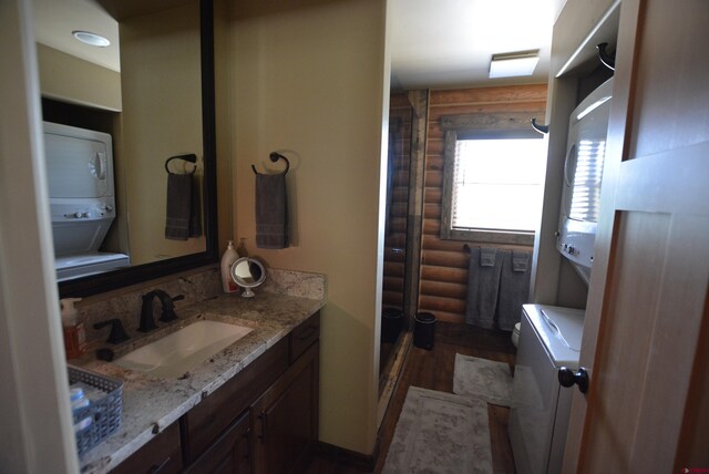 bathroom featuring wood-type flooring, stacked washer and clothes dryer, rustic walls, and walk in shower