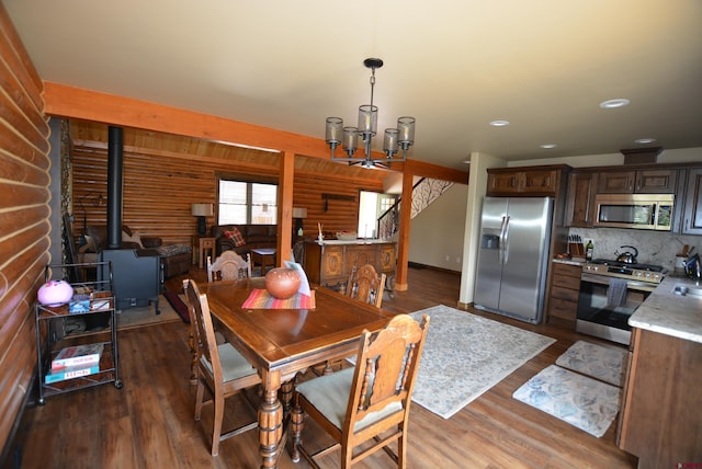 dining space featuring dark wood-type flooring, a chandelier, and a wood stove