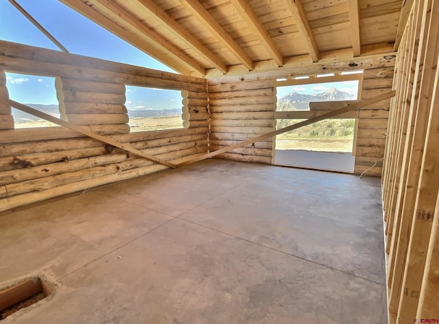 spare room featuring concrete flooring, wood ceiling, log walls, and lofted ceiling with beams