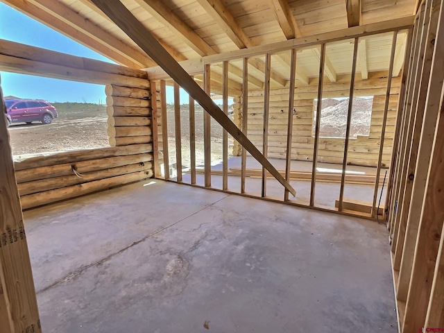 misc room with lofted ceiling with beams, wooden ceiling, and concrete flooring