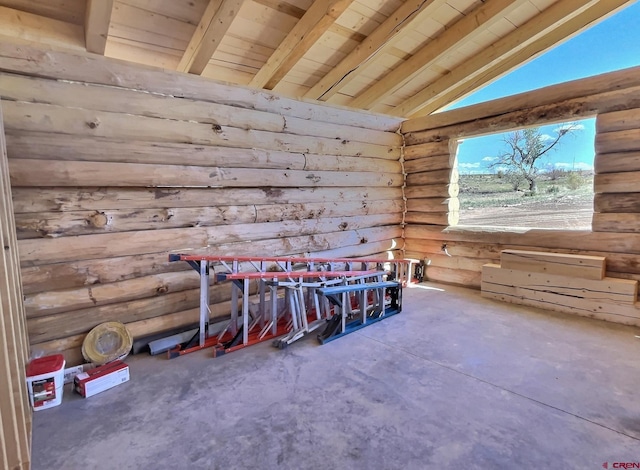 misc room featuring wood ceiling, rustic walls, vaulted ceiling with beams, and concrete flooring