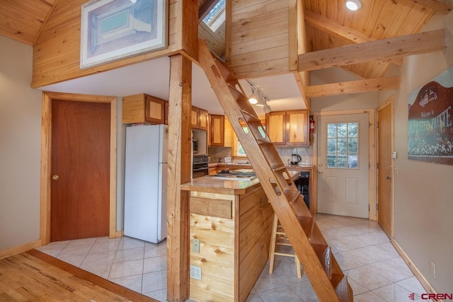 kitchen with tasteful backsplash, stainless steel appliances, light tile flooring, and wooden ceiling