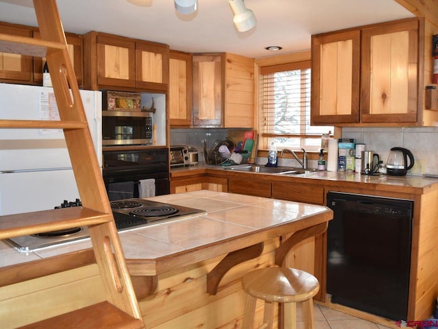 kitchen featuring sink, tile counters, tasteful backsplash, and black appliances