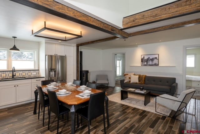 dining room featuring dark hardwood / wood-style flooring, a healthy amount of sunlight, sink, and beamed ceiling