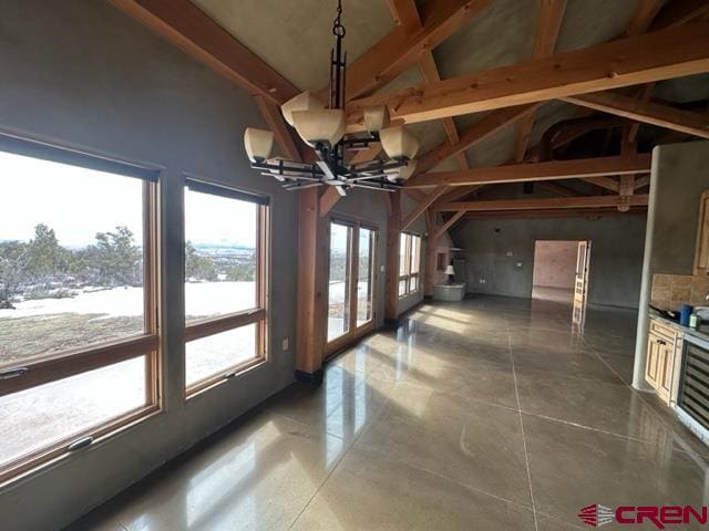 unfurnished dining area with a notable chandelier, dark tile flooring, and lofted ceiling with beams