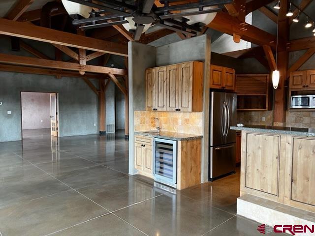 kitchen featuring tasteful backsplash, stainless steel appliances, beverage cooler, sink, and a high ceiling