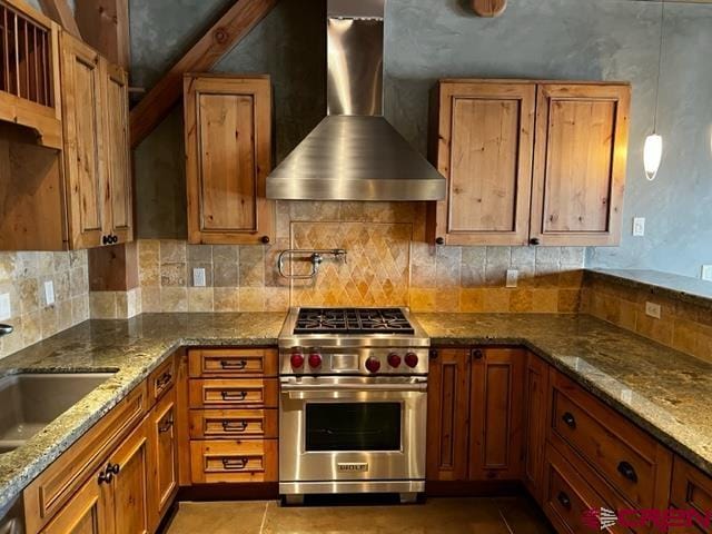 kitchen with wall chimney range hood, light stone counters, tasteful backsplash, and luxury stove