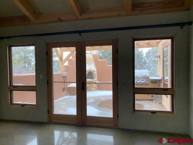 doorway with a wealth of natural light, beamed ceiling, and light tile floors