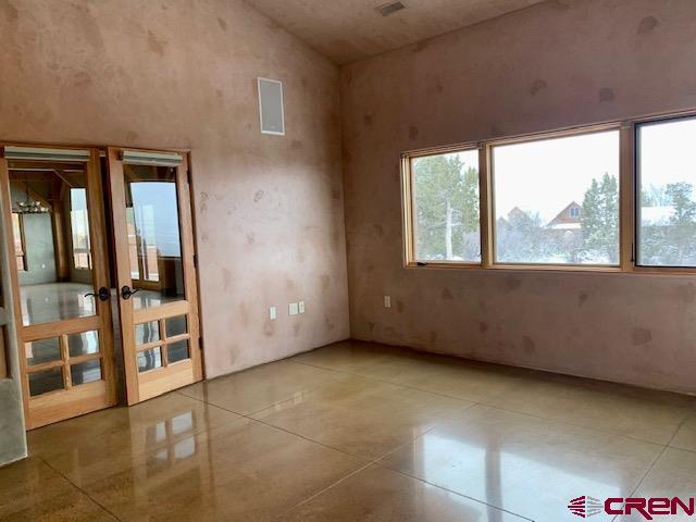 tiled spare room with french doors and high vaulted ceiling