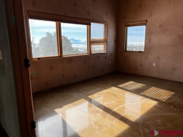 empty room with light tile flooring and plenty of natural light