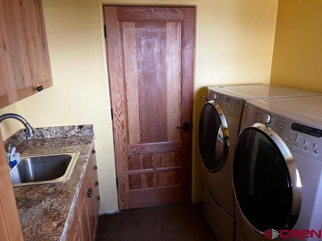 laundry room featuring dark tile flooring, independent washer and dryer, cabinets, and sink