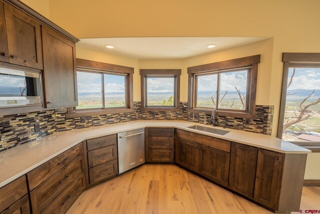 kitchen with backsplash, light hardwood / wood-style floors, appliances with stainless steel finishes, and sink