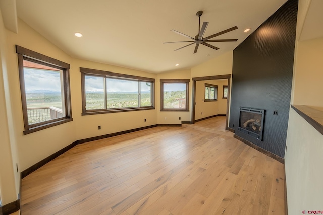 unfurnished living room featuring a wealth of natural light, ceiling fan, light wood-type flooring, a fireplace, and vaulted ceiling