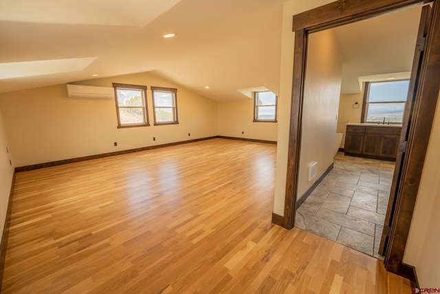 additional living space with sink, light tile floors, vaulted ceiling, and a wall mounted AC