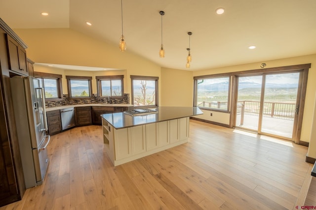 kitchen featuring pendant lighting, stainless steel appliances, backsplash, dark brown cabinetry, and light hardwood / wood-style flooring