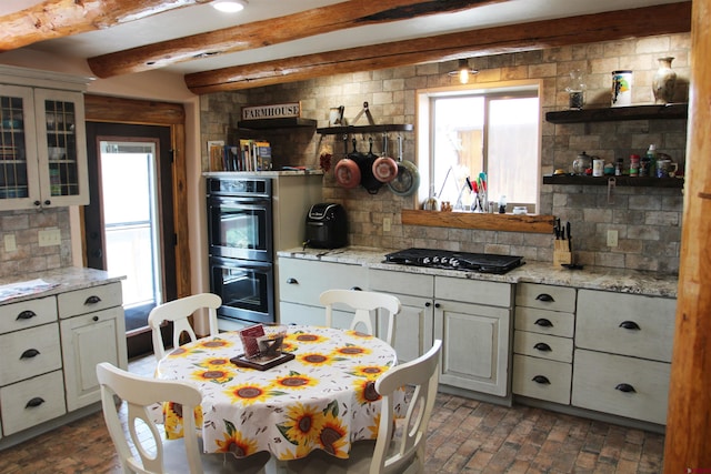 kitchen featuring a wealth of natural light, backsplash, stainless steel double oven, and beamed ceiling