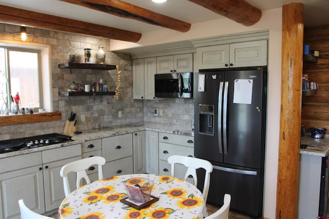 kitchen featuring tasteful backsplash, light stone counters, black appliances, and beamed ceiling