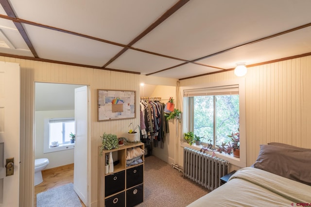 bedroom with radiator, ensuite bathroom, light hardwood / wood-style floors, and a closet