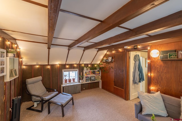 sitting room featuring wood walls, light carpet, radiator heating unit, and lofted ceiling with beams