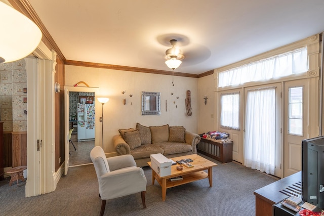 living room featuring ceiling fan, ornamental molding, and dark carpet