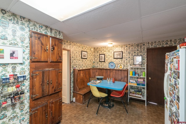 dining area featuring a paneled ceiling and dark tile flooring