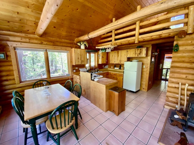 kitchen with white fridge, log walls, light tile floors, and kitchen peninsula