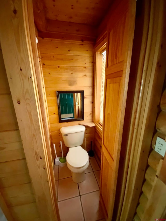 bathroom featuring wood walls, tile floors, and toilet